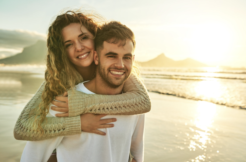 Gelukkig stel op het strand bij zonsondergang — meer regelmaat in je cyclus begint met inzicht