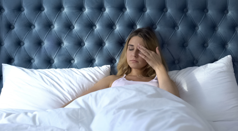 Vrouw in bed met PMS klachten — hulp bij premenstruele klachten